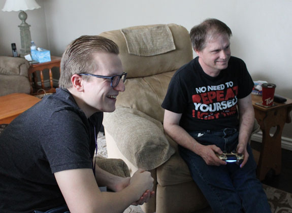 Two smiling young men playing video games in a living room