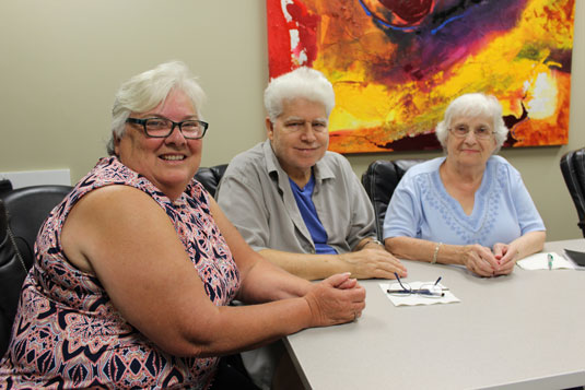 Three smiling people seated around a table