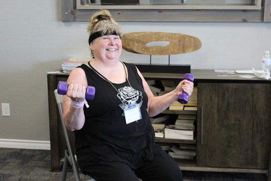 A smiling seated woman lifting hand weights