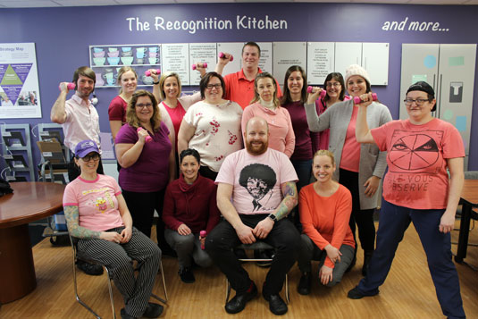 A large group of smiling people wearing pink shirts