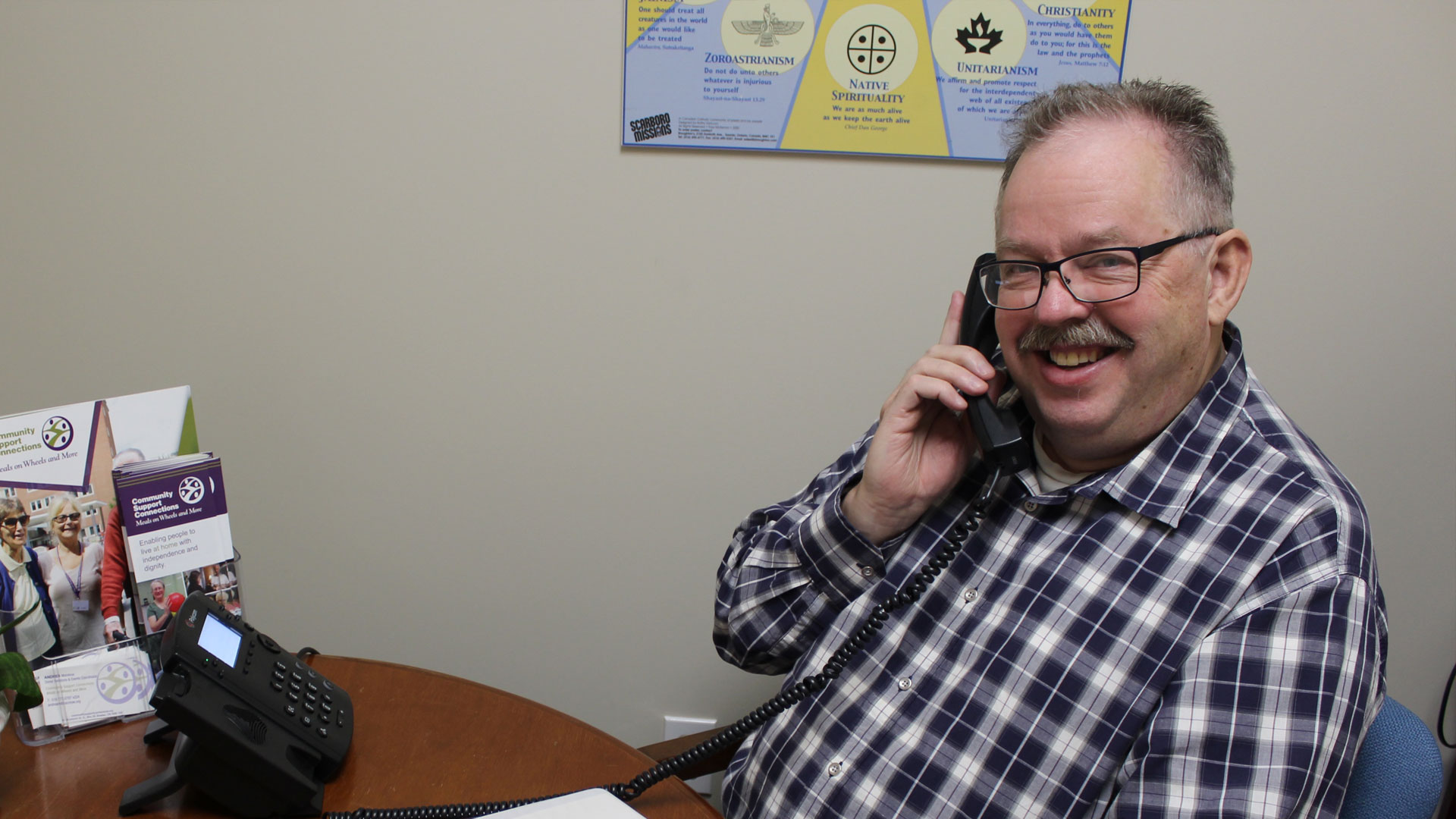 A smiling older man talking on a telephone