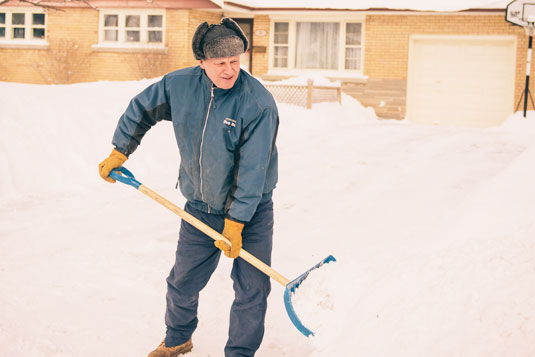 A man shovelling snow off of a driveway